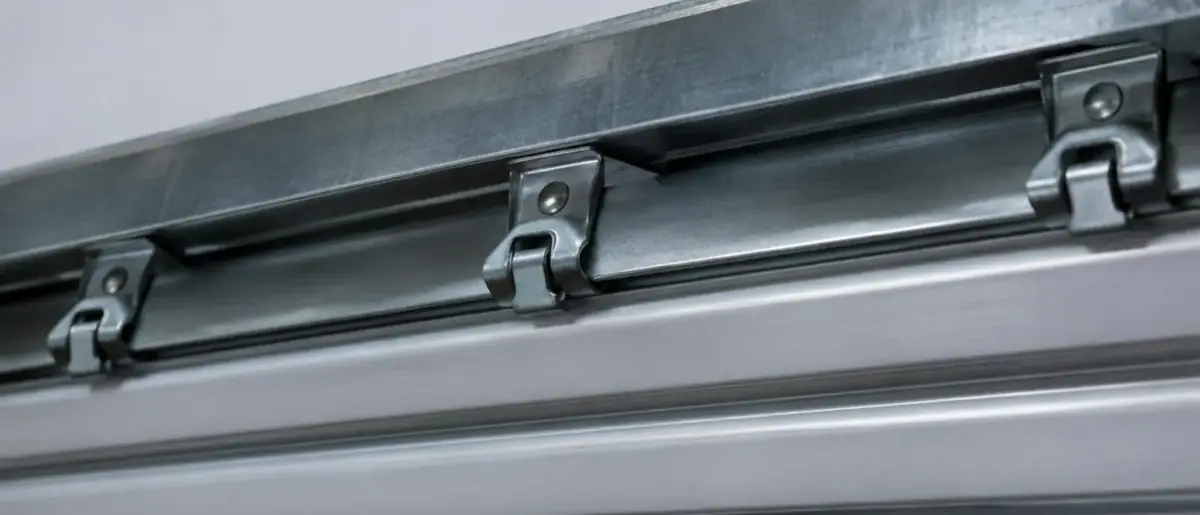 Attaches rigides en métal fixées en haut d'un tablier de volet roulant, gros plan